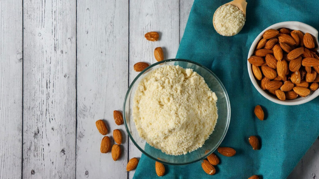harina de almendras en un bowl con un bowl de almendras enteras